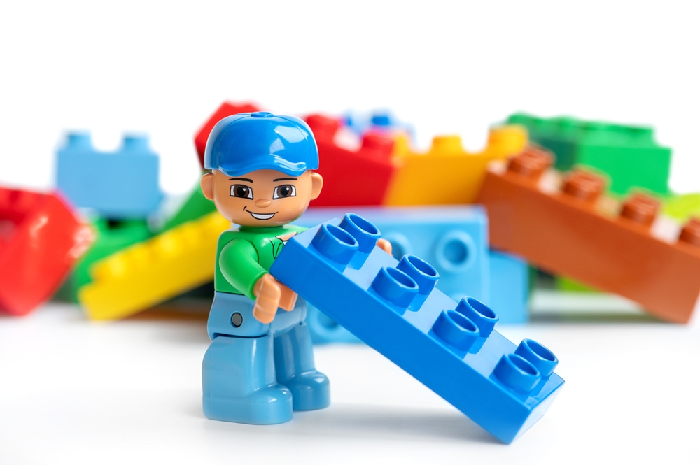 A Lego character holding an 8 stud brick